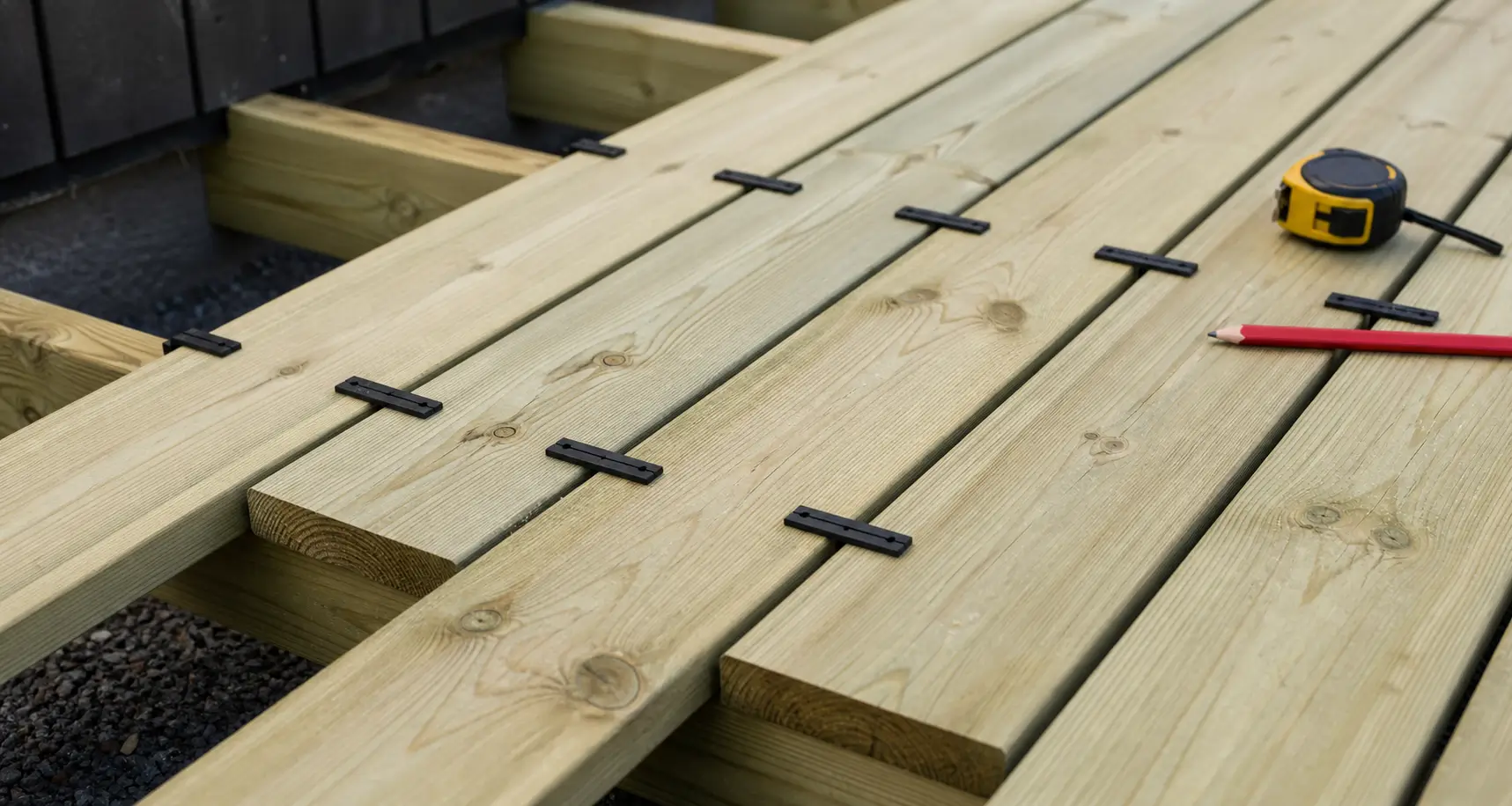 Trykkimpregnerte terrassebord med jevne avstandsklosser mellom bordene under montering
